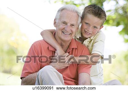Stock Image - Grandfather and grandson outdoors smiling. Fotosearch