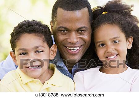 Stock Photo - Man and two young children outdoors smiling. Fotosearch