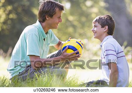 Man and young boy outdoors with soccer ball smiling View Large Photo Image Stock Photograph - Man and young boy outdoors with soccer ball smiling. Fotosearch