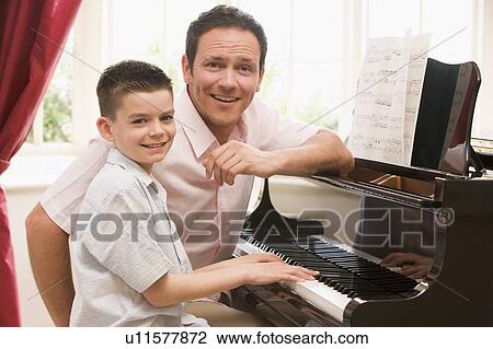 Stock Image - Man and young boy playing piano and smiling. Fotosearch