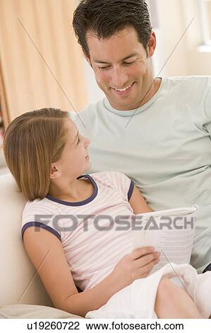 Man and young girl in living room reading book and smiling View Large Photo Image Stock Image - Man and young girl in living room reading book and smiling. Fotosearch