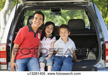 Stock Photography - Man with two children sitting in back of van smiling. Fotosearch