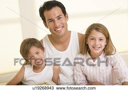 Man with two young children sitting in bed smiling View Large Photo Image Stock Image - Man with two young children sitting in bed smiling. Fotosearch