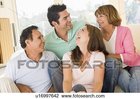 Two couples sitting in living room smiling and laughing View Large Photo Image Stock Image - Two couples sitting in living room smiling and laughing. Fotosearch