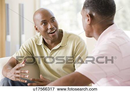 Two men in living room talking and smiling View Large Photo Image Stock Photo - Two men in living room talking and smiling. Fotosearch