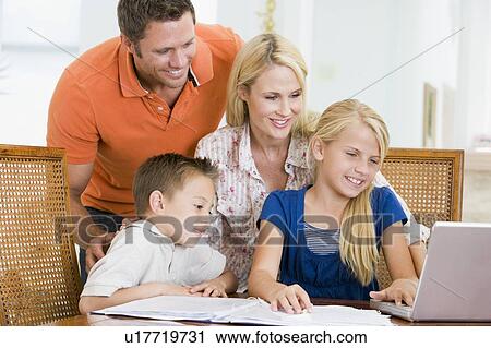 Couple helping two young children with laptop do homework in dining room View Large Photo Image Stock Image - Couple helping two young children with laptop do homework in dining room. Fotosearch