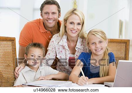 Stock Photo - Couple helping two young children with laptop do homework in dining room. Fotosearch