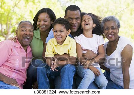 Extended family sitting outdoors smiling View Large Photo Image Picture - Extended family sitting outdoors smiling. Fotosearch