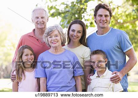 Stock Image - Extended family standing in park smiling. Fotosearch