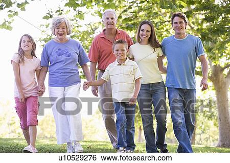 Extended family walking in park holding hands and smiling View Large Photo Image Stock Photograph - Extended family walking in park holding hands and smiling. Fotosearch
