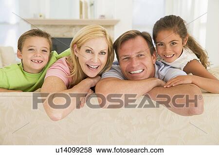 Stock Photo - Family sitting in living room smiling. Fotosearch