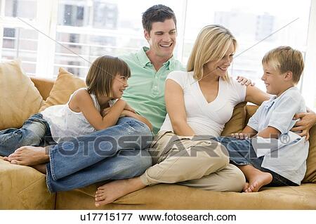 Stock Photo - Family sitting in living room smiling. Fotosearch