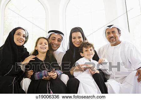 Stock Photograph - Family sitting in living room smiling (high key/selective focus). Fotosearch