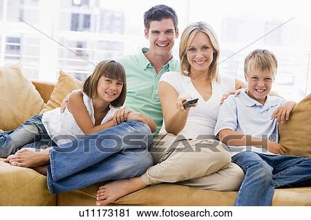Family sitting in living room with remote control smiling View Large Photo Image Stock Image - Family sitting in living room with remote control smiling. Fotosearch