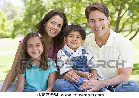 Family sitting outdoors smiling View Large Photo Image Picture - Family sitting outdoors smiling. Fotosearch