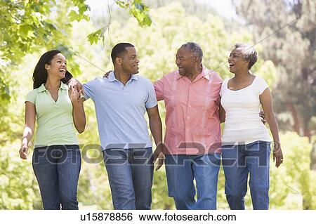 Two couples walking outdoors arm in arm smiling View Large Photo Image Stock Photograph - Two couples walking outdoors arm in arm smiling. Fotosearch
