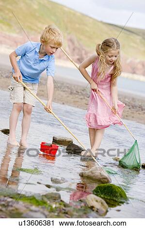 Brother and sister at beach with nets and pail View Large Photo Image Stock Image - Brother and sister at beach with nets and pail. Fotosearch
