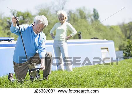 Couple outdoors by lake with boat View Large Photo Image Stock Photo - Couple outdoors by lake with boat. Fotosearch