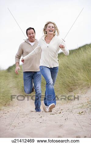 Couple running at beach smiling View Large Photo Image Stock Photo - Couple running at beach smiling. Fotosearch