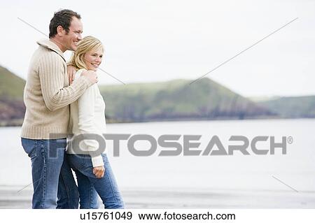 Stock Photo - Couple standing on beach smiling. Fotosearch