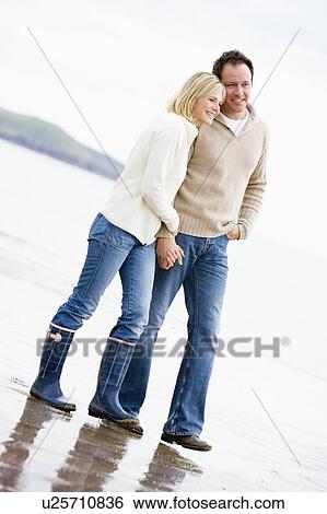 Couple walking on beach holding hands smiling View Large Photo Image Stock Photograph - Couple walking on beach holding hands smiling. Fotosearch