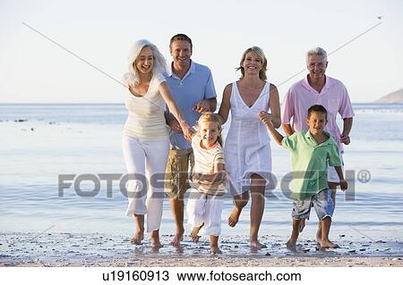 Stock Image - Extended family walking on beach. Fotosearch