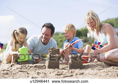 Family on beach making sand castles smiling View Large Photo Image Stock Image - Family on beach making sand castles smiling. Fotosearch