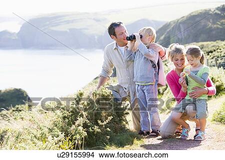 Picture - Family on cliffside path using binoculars and smiling. Fotosearch