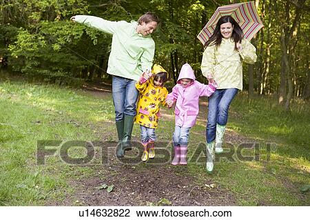 Family outdoors skipping with umbrella smiling View Large Photo Image Stock Image - Family outdoors skipping with umbrella smiling. Fotosearch