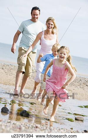 Picture - Family running at beach smiling. Fotosearch
