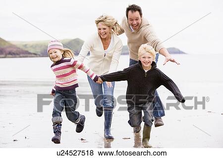 Stock Photo - Family running on beach holding hands smiling. Fotosearch