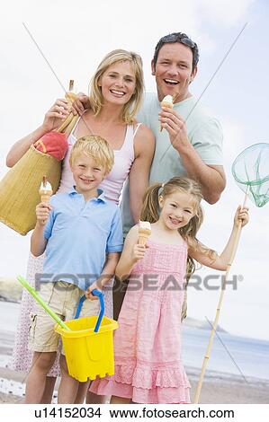 Picture - Family standing at beach with ice cream smiling. Fotosearch