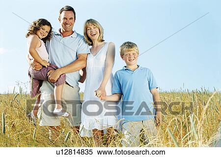 Stock Photography - Family standing outdoors holding hands smiling. Fotosearch