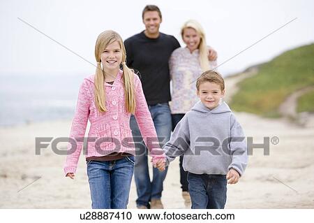 Stock Image - Family walking at beach holding hands smiling. Fotosearch