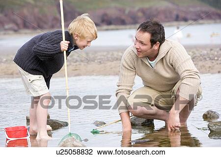 Stock Image - Father and son at beach fishing. Fotosearch