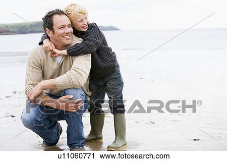 Stock Image - Father and son at beach smiling. Fotosearch
