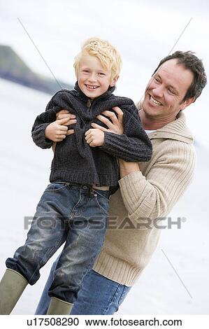 Father holding son at beach smiling View Large Photo Image Stock Image - Father holding son at beach smiling. Fotosearch
