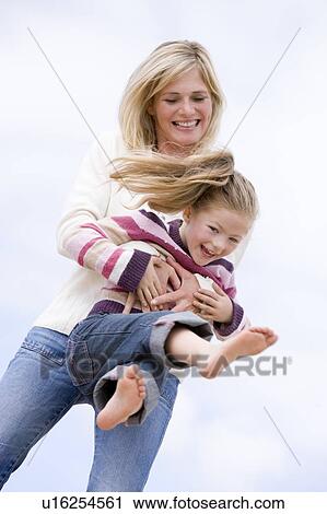 Stock Image - Mother and daughter playing on beach smiling. Fotosearch