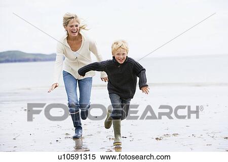 Stock Photography - Mother and son running on beach smiling. Fotosearch