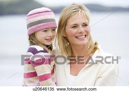 Stock Photography - Mother holding daughter at beach smiling. Fotosearch