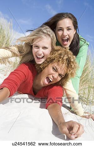 Three women posing on a sand hill View Large Photo Image Stock Image - Three women posing on a sand hill. Fotosearch