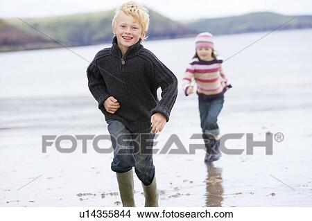 Two young children running on beach smiling View Large Photo Image Picture - Two young children running on beach smiling. Fotosearch