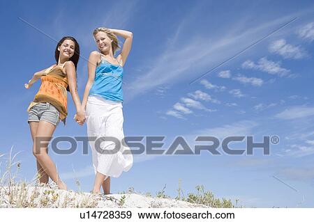 Two young women posing on a sand hill View Large Photo Image Stock Photo - Two young women posing on a sand hill. Fotosearch