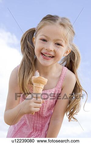 Young girl outdoors eating ice cream cone and smiling View Large Photo Image Stock Image - Young girl outdoors eating ice cream cone and smiling. Fotosearch