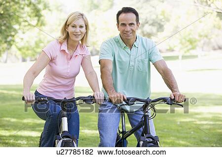 Couple on bikes outdoors smiling View Large Photo Image Stock Image - Couple on bikes outdoors smiling. Fotosearch