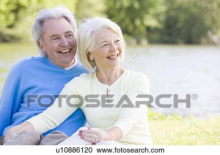 Couple outdoors at park by lake smiling View Large Photo Image Stock Image - Couple outdoors at park by lake smiling. Fotosearch