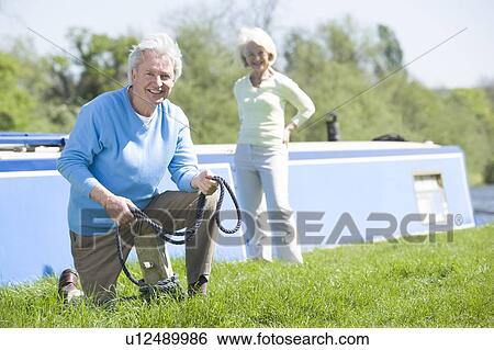 Couple outdoors by lake with boat smiling View Large Photo Image Stock Photograph - Couple outdoors by lake with boat smiling. Fotosearch