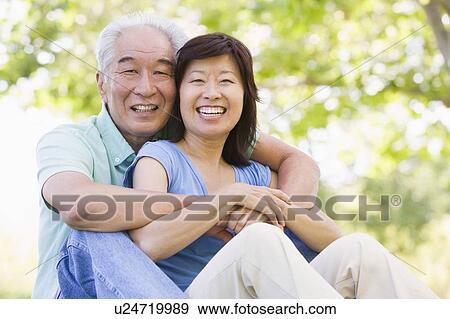 Couple relaxing outdoors in park smiling View Large Photo Image Stock Photo - Couple relaxing outdoors in park smiling. Fotosearch