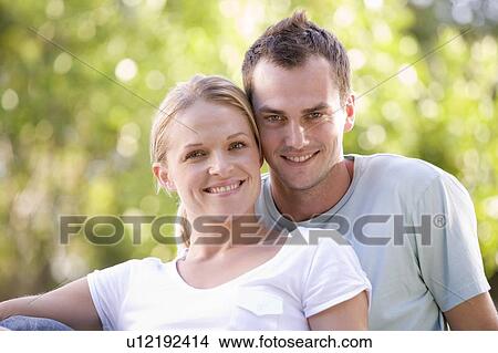 Picture - Couple sitting outdoors smiling. Fotosearch
