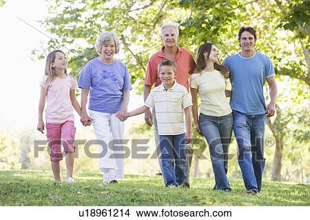 Extended family walking in park holding hands and smiling View Large Photo Image Picture - Extended family walking in park holding hands and smiling. Fotosearch